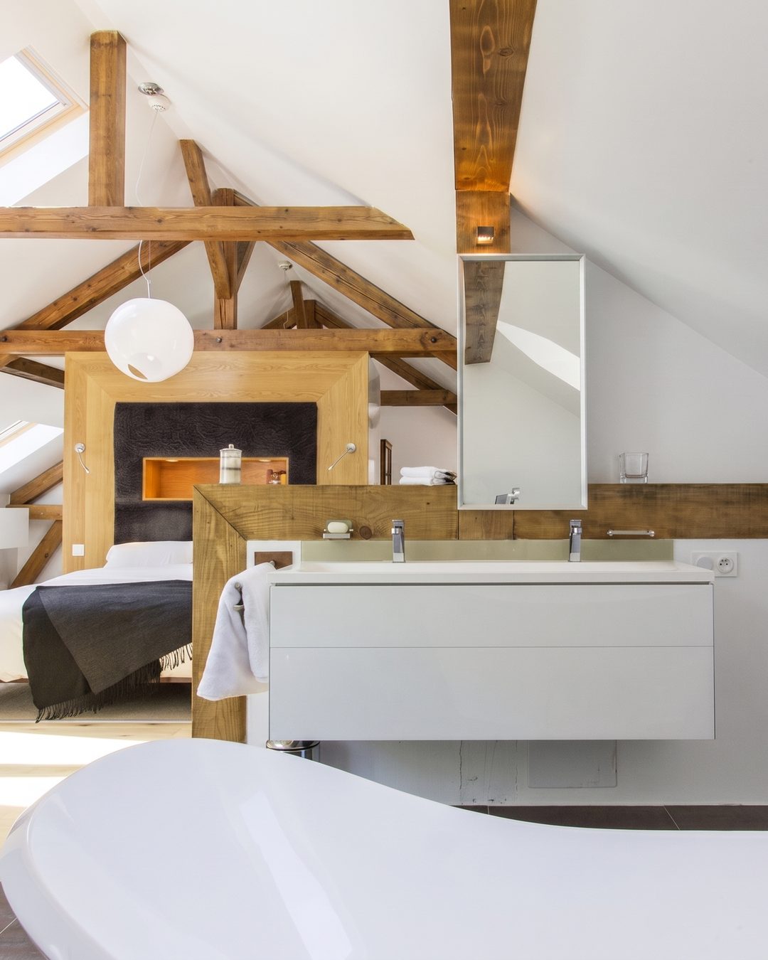 Attic ensuite with exposed timber trusses, twin-basin vanity and freestanding bath