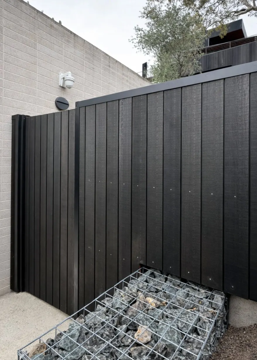 Dark vertical cladding beside a stone-filled gabion
